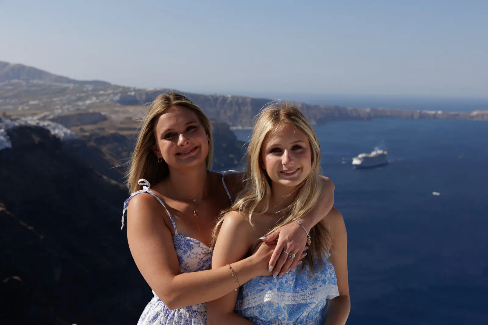 Two family members in blue dresses overlooking the Santorini caldera