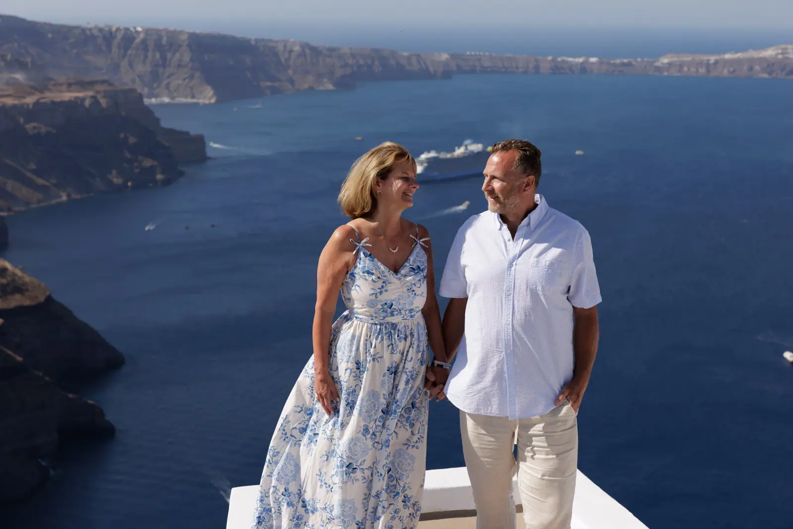 Couple smiling at one another against the Santorini sea view