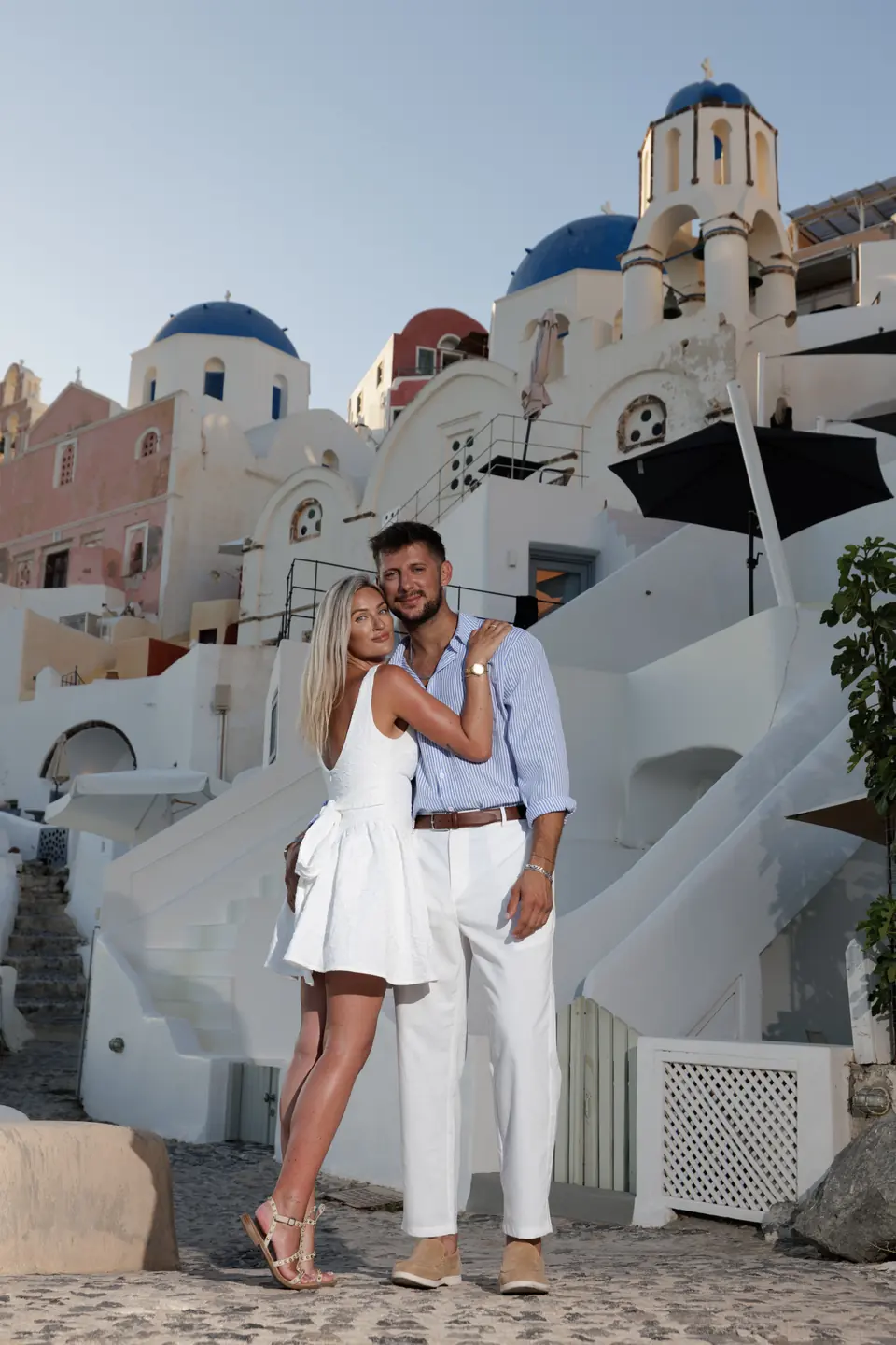 Charlie and Kayce standing together on a white Santorini stairway