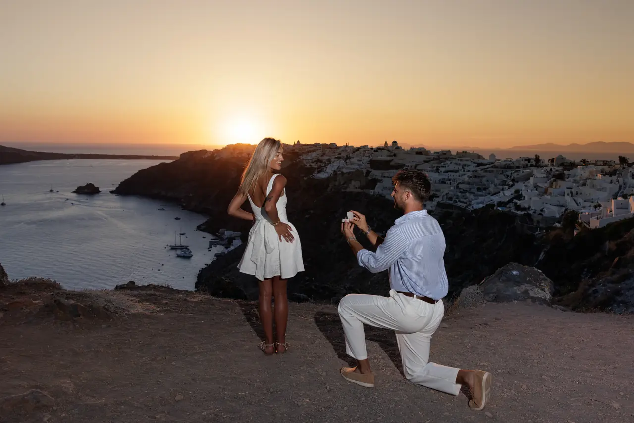 Charlie on one knee with Kayce against the Santorini sunset