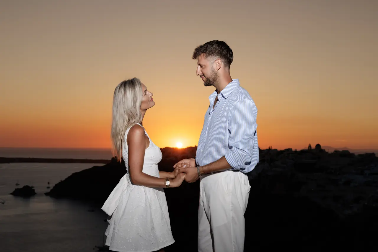 Charlie and Kayce holding hands beside the caldera at sunset